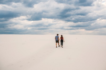 the girl and the guy are walking in the desert, the couple in love holds each others hands, but they are lost in the desertの写真素材