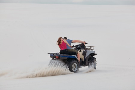 The guy and the girl ride a quad bike in the desert, having fun and enjoying, a couple of loversの写真素材