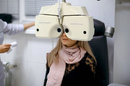 Professional female ophthalmologist checks the eyes of a girl