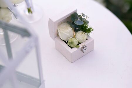 wedding gold rings decorated with flowers on a white background in a wooden box on the table for a...