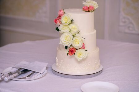 Beautiful wedding cake with creamy red roses, white delicious cake at the weddingの写真素材