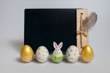 Golden eggs with an easter bunny on the background of a chalk board, on a white background, easter...