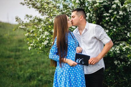 Happy young couple holding ultrasound of their baby in hands, future parentsの写真素材