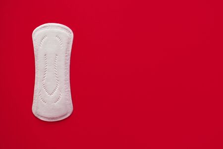 One menstrual pad on a red background, top view, place for text