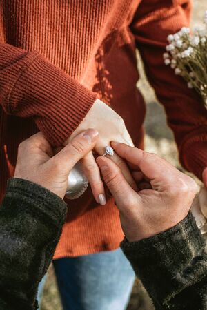 The guy offers his beloved girl to marry him. A man puts a wedding ring on the finger of his woman, she said yes. casual style, marriage proposal in the park, a guy kneeling