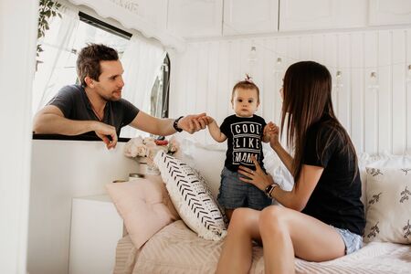husband and wife play with their child, dad, mom and daughter, a woman holds her daughter by the hand, a very cheerful and beautiful familyの写真素材
