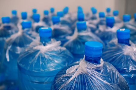 A row of large bottles of drinking water for a cooler. Water delivery. Packed and ready to be shipped to customers, blue bottles, finished goods warehouse, clean waterの写真素材
