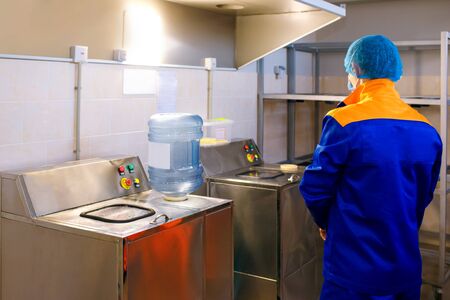 A drinking water treatment plant, a factory worker inspects a plastic bottle, monitors cleanliness, a drinking water plant, plastic processing, clean water is a guarantee of healthの写真素材