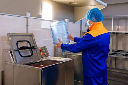A drinking water treatment plant, a factory worker inspects a plastic bottle, monitors cleanliness, a drinking water plant, plastic processing, clean water is a guarantee of healthの写真素材