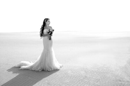 bride in the desert stands with a bouquet, black and white photo, sunsetの写真素材