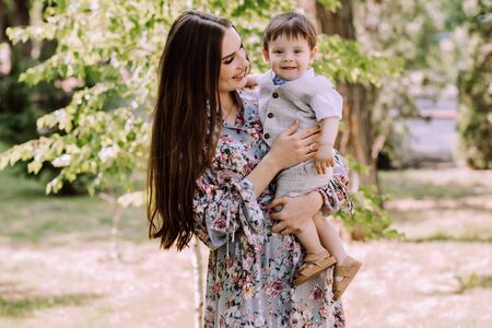 mother holds one year old son in her arms, beautiful evening light, family for a walk