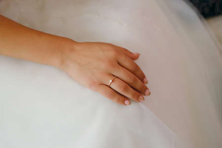 bride with engagement ring, female hand on a white wedding dress