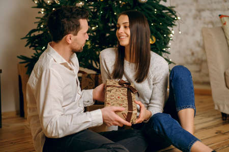 Merry Christmas holidays and family concept. Cute smiling charming man and woman unfold a gift
