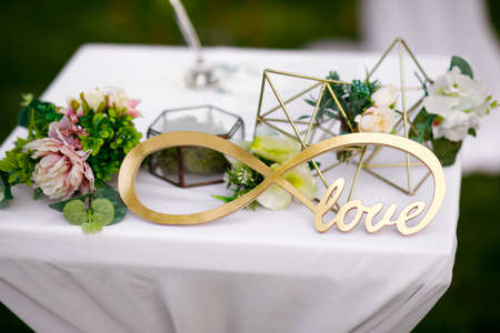 Outdoor wedding ceremony, decorated with a table with fresh flowers, an infinity sign and a glass box under the ringsの写真素材