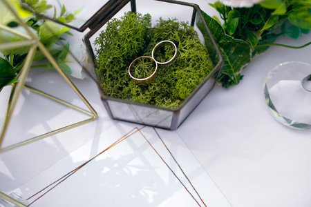 table for the wedding ceremony decorated with flowers and wedding rings of the newlyweds in a glass boxの写真素材
