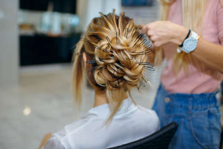 professional hairdresser makes young beautiful bride a wedding hairstyle in the morning before the weddingの写真素材