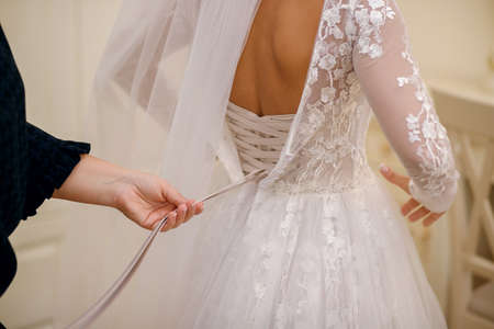 On the wedding day, the bride wears a white wedding dress. A faithful friend helps to tie ribbons on...