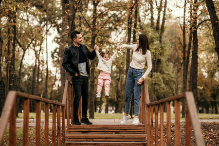 dad and mom are walking with their daughter in the parkの写真素材