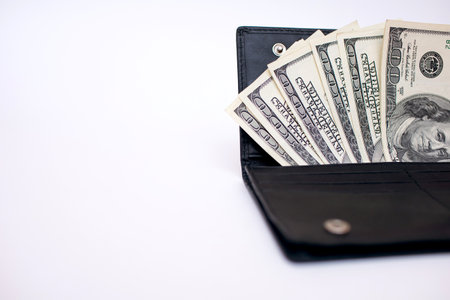 Cash from one hundred dollar bills in a wallet on a white background