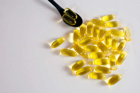 Fish oil capsules on white background with free space for text. In a spoonful of fish oil capsules. Food supplement to improve heart function and prevent blood clots. Animal fat omega-3 omega-6の写真素材