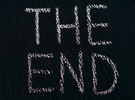 writing The End in chalk on a rough black board to indicate the end of the viewing or processの写真素材