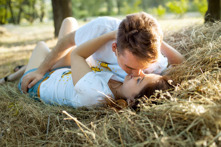 A man and a woman in love lie in the hay and kissの写真素材