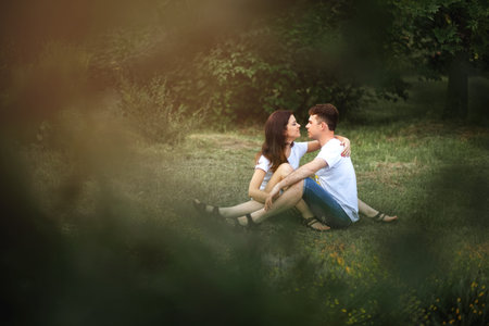 A guy and a girl are sitting on the grass and looking at each other in the parkの写真素材