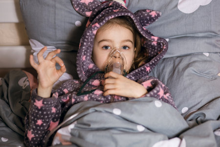 A little girl is being treated for a cough at home using an inhalerの写真素材