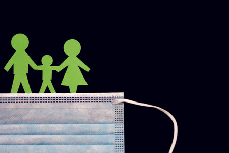 Protective mask from infections and green paper men in the form of a family on a black backgroundの写真素材