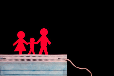 Protective mask from infections and red paper men in the form of a family on a black backgroundの写真素材