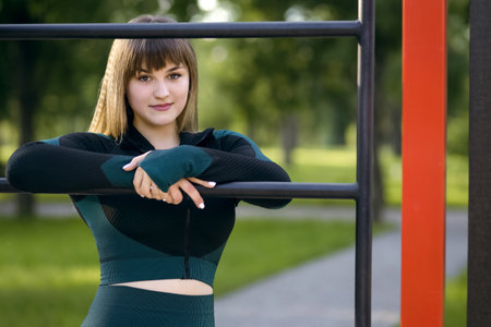 Portrait of a sporty woman model in tight sportswear at the horizontal bar. A young brunette is...