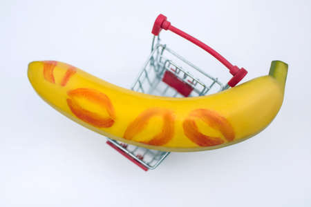 Big ripe banana with kisses in the form of lipstick on a trolley on a white background in a supermarket top view. The concept of buying sexual toys for sex or healthy food products for male powerの写真素材