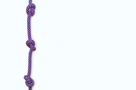 Multicolored rope with three knots on a white background. Blue-pink strong rope with free space for...