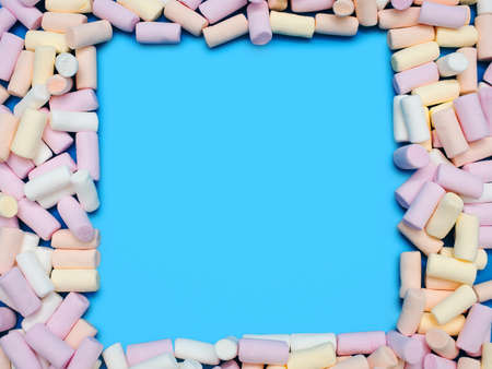 A small colored marshmallow is laid out as a frame on a blue background with an empty space for text...