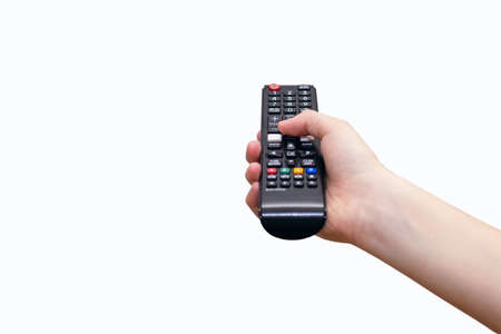 A human hand holds a TV remote control on a white background and presses a button. Control panel...