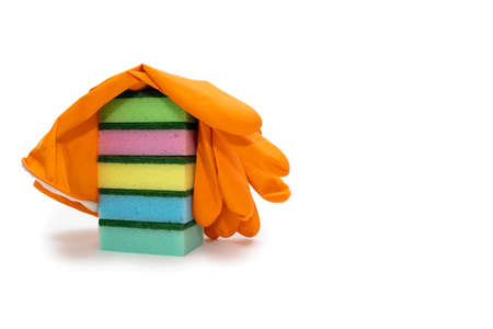 Multi-colored sponges for washing and cleaning stacked and covered with an orange glove on a white...
