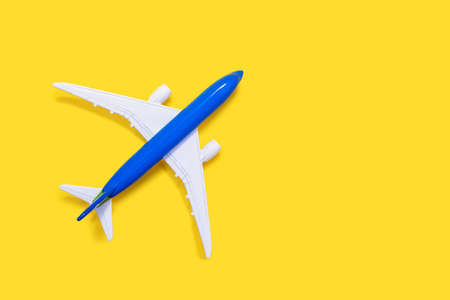 Aircraft model on a yellow background with free space for text or advertising. Tourism or freight transport concept. Toy airplane on a red background with a top viewの写真素材