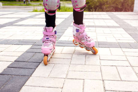 The girl rides on pink roller skates with a view of her legs. Part of the body in the form of legs with rollers for skating close-up. The concept of spending free time with health benefitsの写真素材