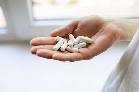 Hand of a man with white pills in his palm. Medical concept of treating diseases with drugs....