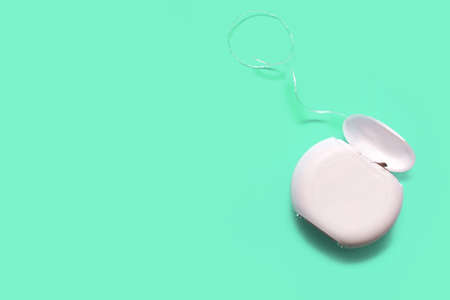 Dental floss for cleaning teeth on a green background with free space for text. The concept of oral care and caries prevention. Dental care products and oral hygieneの写真素材