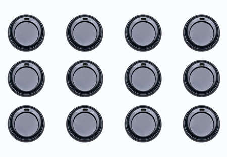 Round plastic black lids for coffee cups on a white background. Background of lids for disposable coffee cups. Environmental problems due to plastic and its use in everyday lifeの写真素材
