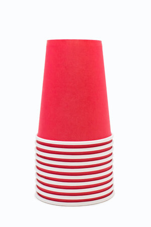 Red disposable cardboard cups stacked in a pile on a white background. Lots of disposable cups stacked one on top of the other and ready to make coffee or drinksの写真素材