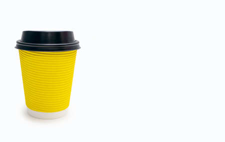 Yellow disposable cardboard cup for coffee with a plastic lid on a white background and free space for text. The concept of fast coffee and its consumptionの写真素材