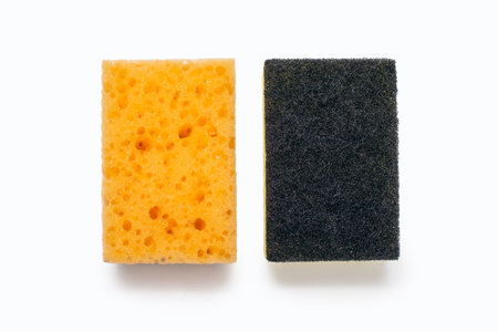 An orange washcloth and a roughened washcloth on a white background in the center of the image. A tool for constant washing dishes and cleaning the house. The concept of cleanliness and orderの写真素材