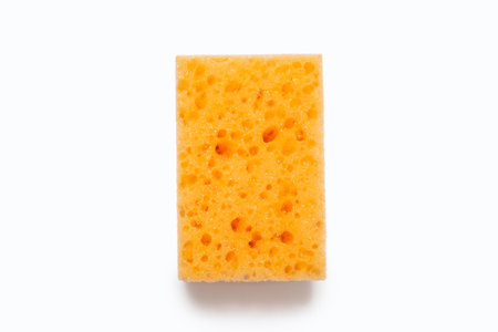 An orange porous washcloth on a white background in the center of the image. Washcloth for washing dishes and daily cleaning in the house. Working tool for cleanliness and care in the houseの写真素材