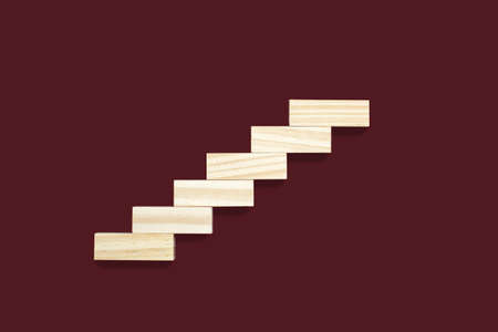Wooden details lined up in the form of steps on a brown background. Wooden rectangles form the shape of the steps. The concept of career growth or rise from the bottom upの写真素材