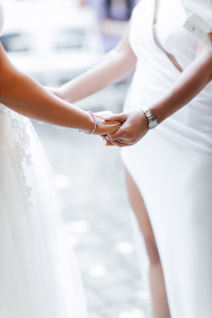 Lesbian wedding of two women who hold each other's hands close-up. Wedding ceremony of two brides. Same-sex LGBT wedding. Lovely women during the wedding ceremonyの写真素材
