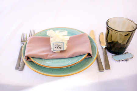 A plate on the table with cutlery and gratitude in the form of the inscription thank you. Table setting and inviting guests to the restaurant. Preparing for the wedding banquetの写真素材