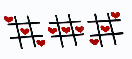 Tic-tac-toe game and red hearts on a white background. The concept of a successful love relationship. Different ways to win in the game of tic-tac-toeの写真素材