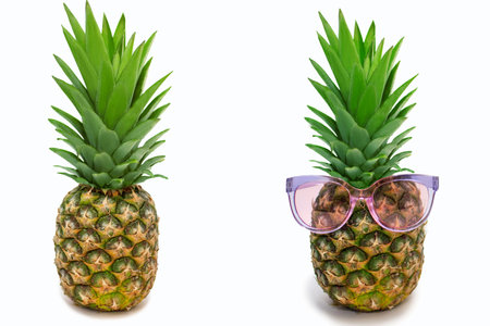 Two ripe pineapples on a white background. Plain pineapple and pineapple with sunglasses. The evolution of fashion in a fruity concept. Free space for textの写真素材